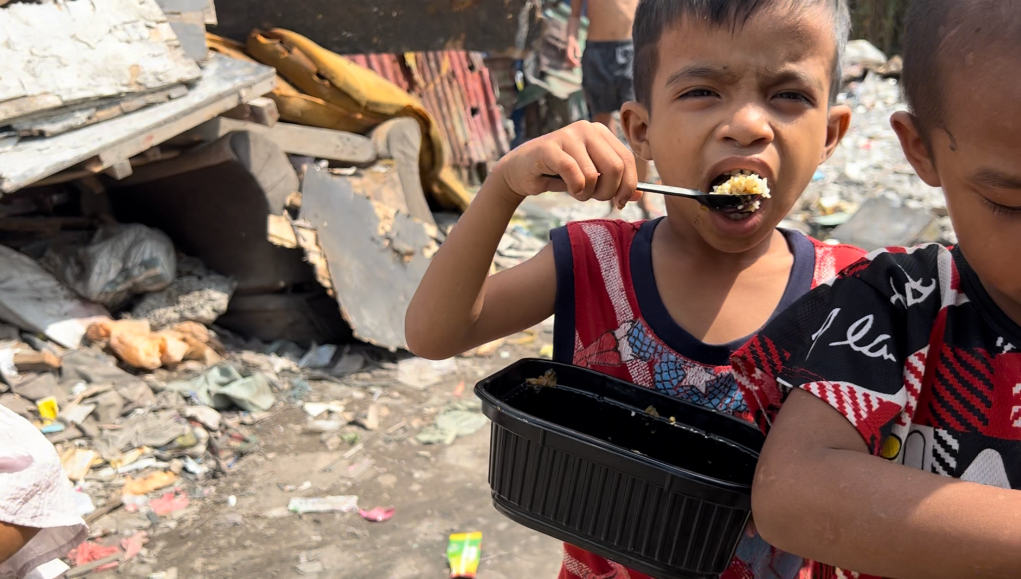 A boy eating curry rice by putting a spoon into a wide-open mouth